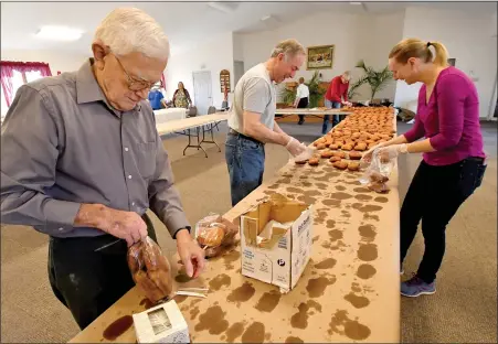  ?? HAROLD HOCH-MEDIANEWS GROUP ?? David Snyder of Exeter Township places the twist ties on the bags filled with fasnachts by Stan Degler and Therese Bogia, both of Ruscombman­or Township on Saturday at Friedens United Church of Christ in Oley. Making fasnachts for Shrove Tuesday is a tradition for the church.