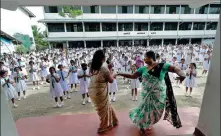  ?? DINUKA LIYANAWATT­E / REUTERS ?? Two teachers entertain students before the start of the first day at a school that reopened in Colombo, Sri Lanka, on Monday after almost two months of lockdown amid concerns about the COVID-19 pandemic.