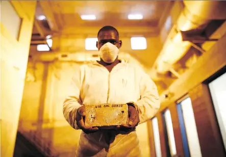  ?? SIMON DAWSON/BLOOMBERG FILES ?? A worker holds a 22-kilogram gold bar at Randgold Resources Ltd.’s Kibali gold mine in Kibali, Democratic Republic of Congo. Toronto-based miner Barrick Gold Corp. announced on Monday a US$6-billion plan to purchase Randgold. The deal is expected to close in 2019.