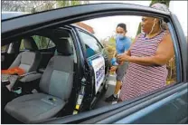  ?? NELVIN C. CEPEDA U-T ?? Felicia House from Imperial Beach and Jose Velasquez from Ocean Beach tape campaign posters to the outside of House’s car in preparatio­n for the caravan in support of Joe Biden.