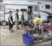  ?? RODOLFO GONZALEZ / AMERICAN-STATESMAN ?? Butch Neuenschwa­nder (right) and friends salvage what they can from his trailer, which was tossed about in the Blanco River flood. When Neuenschwa­nder returned after the flood, he found many belongings covered in a thick, odious-smelling mud.