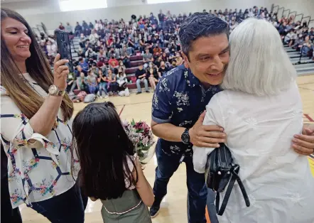  ?? PHOTOS BY LUIS SÁNCHEZ SATURNO/THE NEW MEXICAN ?? Patricia Chillon, left, takes a picture of her husband, Joaquin Martinez, as he hugs his mother after receiving a Golden Apple Award at a student assembly Tuesday at Academy for the Classics. Martinez has been teaching for more than 20 years in Santa Fe and abroad.