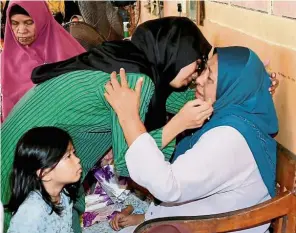  ?? — Bernama ?? Seeking solace: Md Farid’s wife, Datin Farah Syazani Hanis Ismail hugging her mother-in-law Norma (seated) upon arrival at the family home in Kampung Serkat Laut.