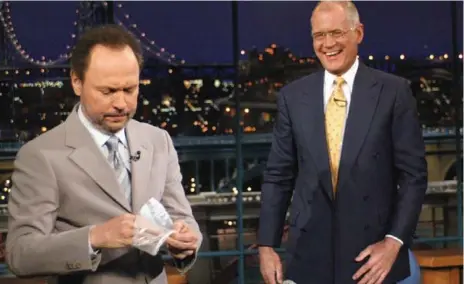 ?? JP FILO/CBS FILE PHOTO ?? Comedian Billy Crystal removes a surgical glove after shaking hands with David Letterman during a taping of The Late Show in 2003.