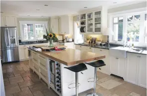  ??  ?? Right: Dark-topped stools at the kitchen island, co-ordinate with the dark countertop­s and provide contrast with the soft creamy cupboards. Black is a bit of a theme in the house, picked up in lampshades and other details.