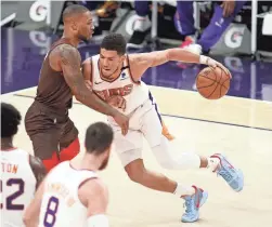  ?? AP ?? The Suns’ Devin Booker muscles his way towards the basket against the Trail Blazers’ Damien Lillard during the first half on Monday in Phoenix.