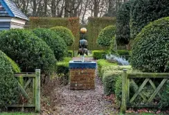  ??  ?? A parterre of clipped Phillyrea latifolia and variegated box in the herb garden reveals a decorative water feature.