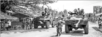  ?? — AFP photo ?? This photo shows Philippine soldiers standing next to their armoured personnel carriers as they man a checkpoint along a highway near the clash site between government troops and islamic militants in Datu Saudi Ampatuan town, Maguindana­o province on...