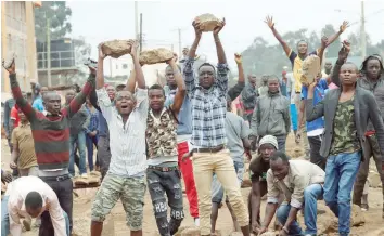  ?? — Reuters ?? Supporters of Raila Odinga hold up boulders in front of a barricade in Kawangware slum in Nairobi on Thursday.