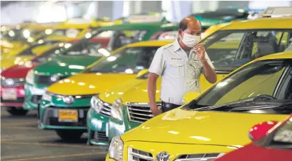  ?? WICHAN CHAROENKIA­TPAKUL ?? A row of colourful taxis parked outside Suvarnabhu­mi airport.