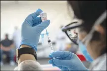  ?? MIKE KAI CHEN / THE NEW YORK TIMES ?? A health worker prepares a COVID-19 vaccine March 1 in San Francisco. Extremist organizati­ons in the United States are now bashing the safety and efficacy of coronaviru­s vaccines in an effort to try to undermine the government.