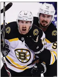  ?? AP/The Canadian Press/FRANK GUNN ?? Boston Bruins
left wing Brad Marchand (left) celebrates his goal with left wing Marcus Johansson during the first period Sunday against the Toronto Maple Leafs in Toronto. Marchand had two goals and an assist as the Bruins won 4-2 to force a Game 7 in their first-round playoff series.