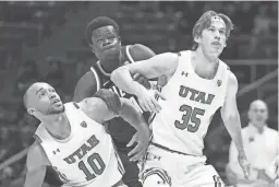  ?? GETTY IMAGES ?? Utah’s Marco Anthony (10) and Branden Carlson box out Arizona’s Oumar Ballo during their game at Jon M. Huntsman Center on Thursday night in Salt Lake City.