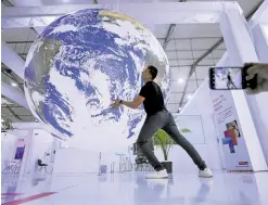  ?? —REUTERS ?? IMMOVABLE OBJECT An attendee poses for a picture near a model Earth during the COP27 climate summit in Sharm elSheikh in Egypt on Saturday.