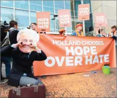  ?? JOHN THYS/AFP ?? Members of campaign group Avaaz, one wearing a mask of the Dutch far-right PVV party leader (left), welcome the victory of the Liberal VVD party in the general election, at the Buitenhof entrance of the Dutch parliament in The Hague yesterday.