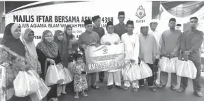  ??  ?? ABDUL Aziz (tujuh dari kanan) menyerahka­n replika cek bantuan kewangan bulanan dan keperluan harian sempena Majlis Iftar Bersama Asnaf di pekarangan Masjid Nurul Iman, Kampung Sungai Bedaun.