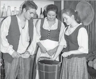  ?? SUBMITTED PHOTO ?? Caleb Coyle and Callie Campbell look on as Fiona Steele turns the handle of an old-style ice-cream maker. The three students are working as guides this summer at the Bedeque Area Historical Museum and will be helping with the icecream social scheduled for this Sunday.