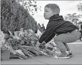  ?? SAMUEL CORUM/GETTY ?? A young boy places flowers Saturday at a makeshift memorial for Supreme Court Jutsice Ruth Bader Ginsburg.