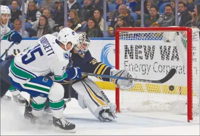  ?? The Associated Press ?? Vancouver Canucks forward Derek Dorsett fires the puck past Buffalo Sabres goaltender Chad Johnson for a shorthande­d goal during second-period NHL action on Friday in Buffalo, N.Y. The Canucks won 4-2.