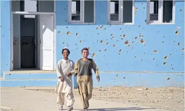  ?? AFP ?? Children walk past their bullet-ridden school in Arghandab district on Thursday.