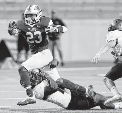  ?? Michael Wyke / Contributo­r ?? C.E. King running back D.K. Hammond, who rushed for 155 yards, runs through a tackle by Huntsville linebacker Calvin Simmons.