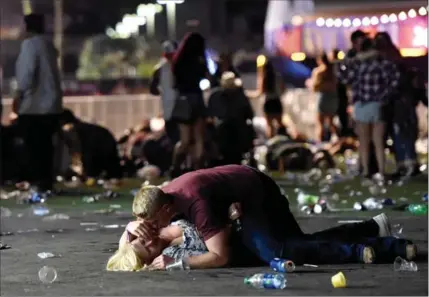  ?? DAVID BECKER, GETTY IMAGES ?? Two people are on the ground as a man fires on a country music festival from a hotel room in downtown Las Vegas. The shooter liked to visit Las Vegas and gamble. Nothing indicated he could become a mass murderer.