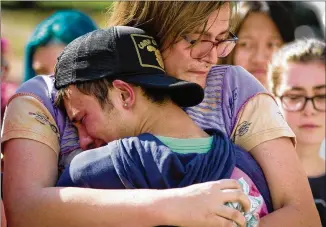  ?? STEVE SCHAEFER / SPECIAL TO THE AJC ?? Mourners hug at a memorial for Georgia Tech student Scout Schultz, 21, on Sunday. Schultz, a computer engineerin­g student at Georgia Tech, was shot late Saturday night by Georgia Tech campus police after allegedly wielding a knife and telling officers...