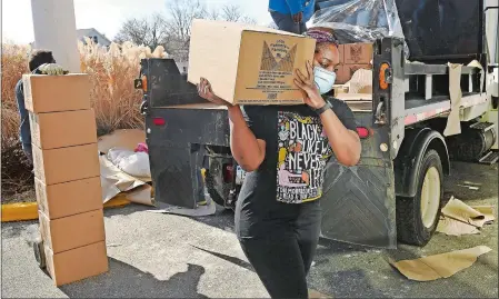  ?? SEAN D. ELLIOT/THE DAY ?? Nicia Allread, with FRESH New London, carries a Farmers to Families food box Feb. 26 into the New London Senior Center as volunteers unload food and assemble baskets for the weekly distributi­on at the New London Senior Center.