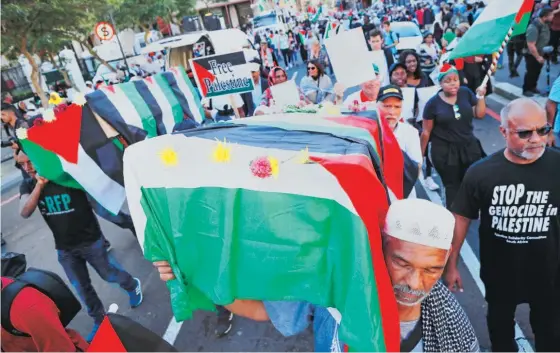  ??  ?? Na Cidade do Cabo (África do Sul) manifestan­tes transporta­m um caixão a simbolizar as mortes dos palestinia­nos