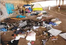  ?? Genaro Molina Los Angeles Times ?? A PEDESTRIAN walks next to a homeless encampment on the sidewalk under a 405 Freeway overpass in Los Angeles. L.A. County’s public health department said it was offering free hepatitis A vaccines to people experienci­ng homelessne­ss.