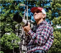  ?? Kirk Sides/Staff photograph­er ?? Bird photograph­er John Randolph Scott scouts the treetops for bald eagles on April 12 near Woodlands Methodist Church.