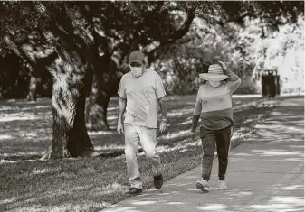  ?? Yi-Chin Lee / Staff photograph­er ?? People wear masks as they walk on a trail April 27 near White Oak Bayou. The act of wearing a mask to prevent more coronaviru­s infections is on its way to becoming a sort of political statement.