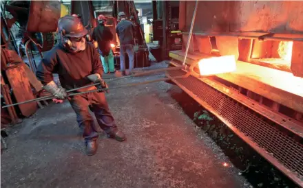  ?? MIKE DE SISTI/MILWAUKEE JOURNAL SENTINEL ?? Rocky Herman, a Milwaukee Forge heater operator, pulls a forged steel billet from a box furnace heated to 1,800 to 2,000 degrees.