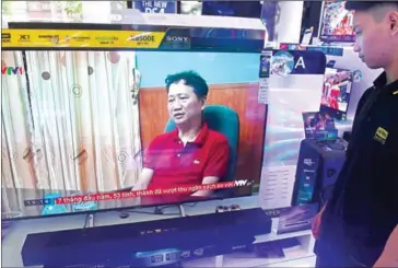  ?? HOANG DINH NAM/AFP ?? A store employee watches a screen showing Trinh Xuan Thanh speaking in a clip aired by Vietnam’s state television VTV, in Hanoi on August 4.