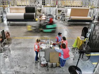  ?? ASSOCIATED PRESS / 2006 ?? A forklift speeds by machines and workers on the production floor of a Mohawk rug manufactur­ing plant in Calhoun. The flooring company has been an economic engine for North Georgia.