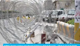  ??  ?? KUWAIT: Cleaning workers seen through barbwire in Jleeb Al-Shuyoukh. —Photo by Fouad Al-Shaikh