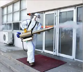  ?? Chinatopix via AP ?? A worker in a protective suit sprays disinfecta­nt at a business Saturday in Qingdao in eastern China’s Shandong Province. China’s death toll from the coronaviru­s rose to 304.