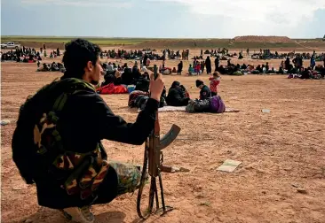  ?? AP ?? A member of US-backed Syrian Democratic Forces (SDF) watches over people who were evacuated out of the last territory held by Islamic State militants, outside Baghouz.