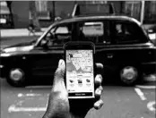  ?? DANIEL LEAL-OLIVAS/GETTY-AFP ?? A smartphone displays the Uber app as a London black cab passes. London won’t renew Uber’s license to operate.