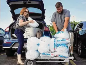  ?? BARBARA J. PERENIC / COLUMBUS DISPATCH ?? Amanda Nyeste, a sales assistant for Cameron Mitchell Premier Events, and Barrett Kinnaman (right) of Whitehall unload bags of ice to donate after the Franklin County Dog Shelter & Adoption Center lost power and had no air conditioni­ng on Tuesday. Kinnaman had previously adopted a dog from the shelter.