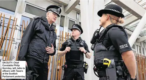  ??  ?? ON DUTY: Chief Constable Philip Gormley, left, talks to officers with Tasers at the Scottish Parliament yesterday