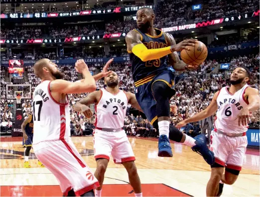  ?? — AP ?? Cleveland Cavaliers’ LeBron James (centre) drives to the basket past Toronto Raptors players during their game on Friday.