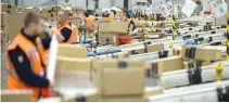  ??  ?? WORKERS prepare customer orders for dispatch as they work around goods stored inside an Amazon.co.uk fulfillmen­t center in Peterborou­gh, England.
