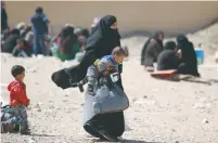  ?? (Rodi Said/Reuters) ?? A WOMAN and a child arrive in the village of al-Mahmudli in northeaste­rn Syria yesterday after fleeing from Raqqa.