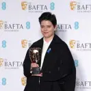  ?? ?? Charlotte Wells poses with the Outstandin­g Debut by a British Writer, Director or Producer Award for Aftersun. Photograph: Dominic Lipinski/Getty Images