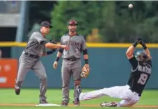  ?? Dustin Bradford, Getty Images ?? Rockies center fielder Charlie Blackmon gets to second base a bit late to break up a double play against the Diamondbac­ks’ Nick Ahmed, left, and Daniel Descalso in a game this season.