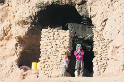  ?? Massoud Hossaini / AP Photos ?? Afghan children outside their cave in Bamiyan province. The bare-bones way of the cave-dwelling families is now under threat as the government relocates residents to transform the man-made grottoes into a global tourist destinatio­n.