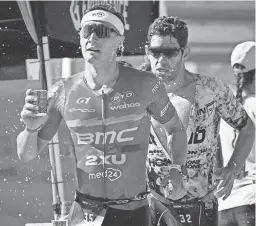  ?? ALEX GOULD/THE REPUBLIC ?? Kristian Hogenhaug (front), and Joe Skipper grab cups of water from one of the stations along the run route during Ironman Arizona in Tempe on Sunday.