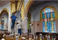  ??  ?? Rudy Rivera, left, and Jimmy Rodriguez paint the sanctuary several days before it is expected to reopen for public Masses.