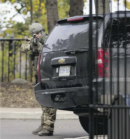  ?? Justin Tang / The Cana dian Press ?? An armed RCMP officer takes position at the gate of 24 Sussex Dr., the official residence
of Prime Minister Stephen Harper on Wednesday after a shooting on Parliament Hill.